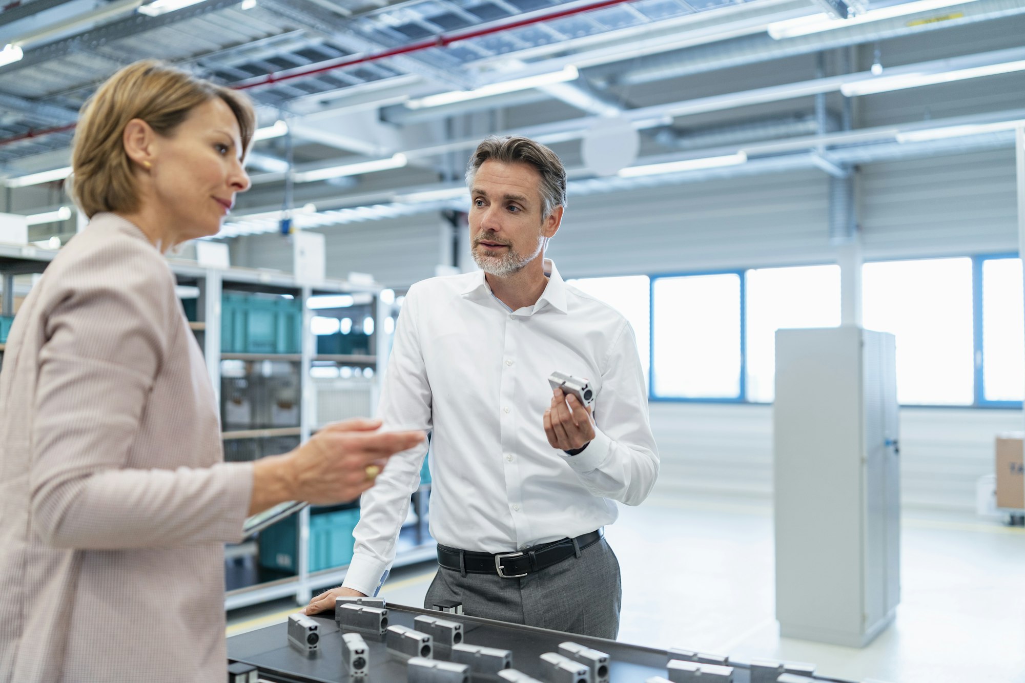 Businessman and businesswoman talking in a modern factory hall